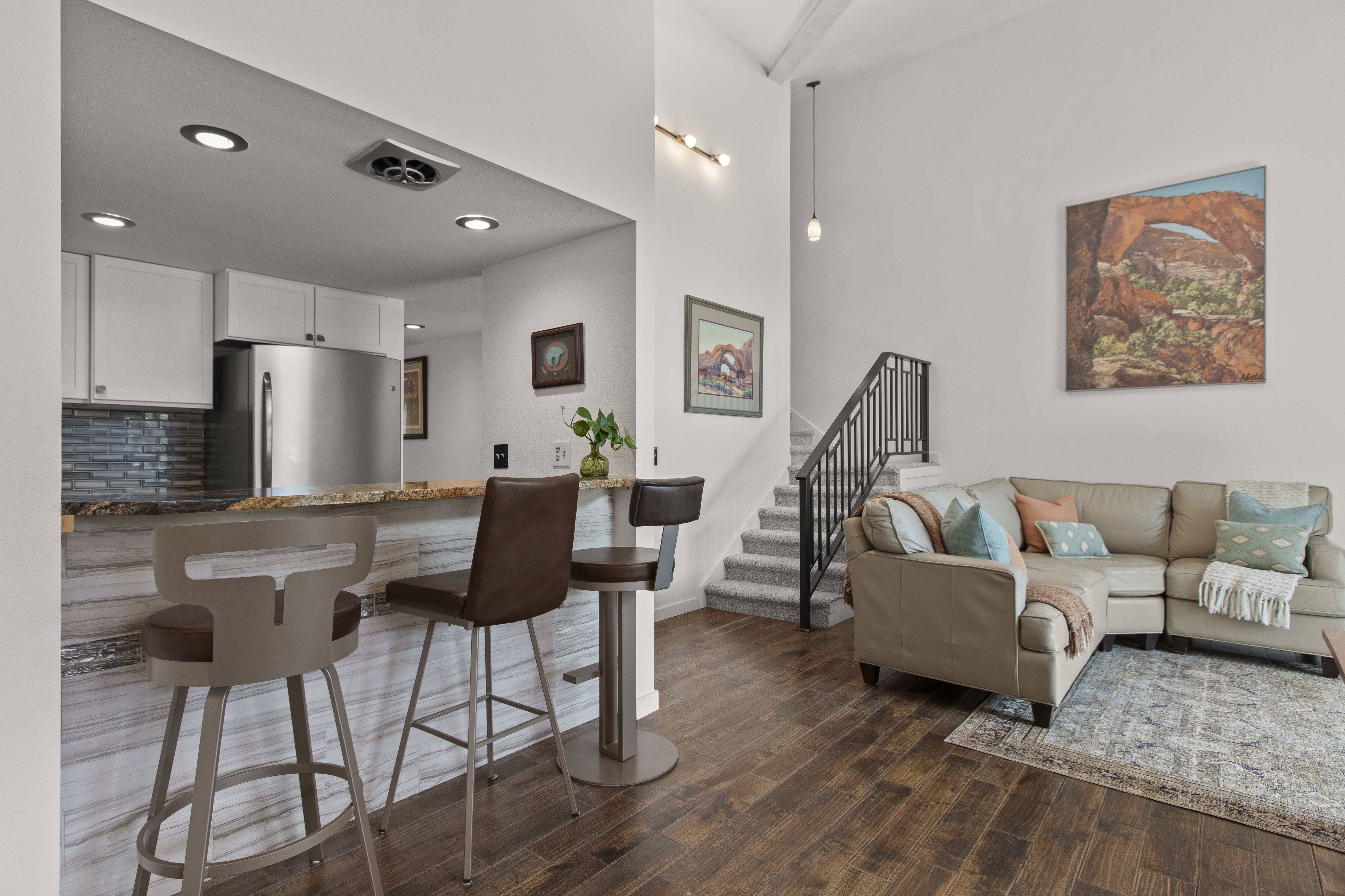 Living area with dark wood-type flooring, recessed lighting, and a high ceiling