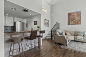 Living area with dark wood-type flooring, recessed lighting, and a high ceiling