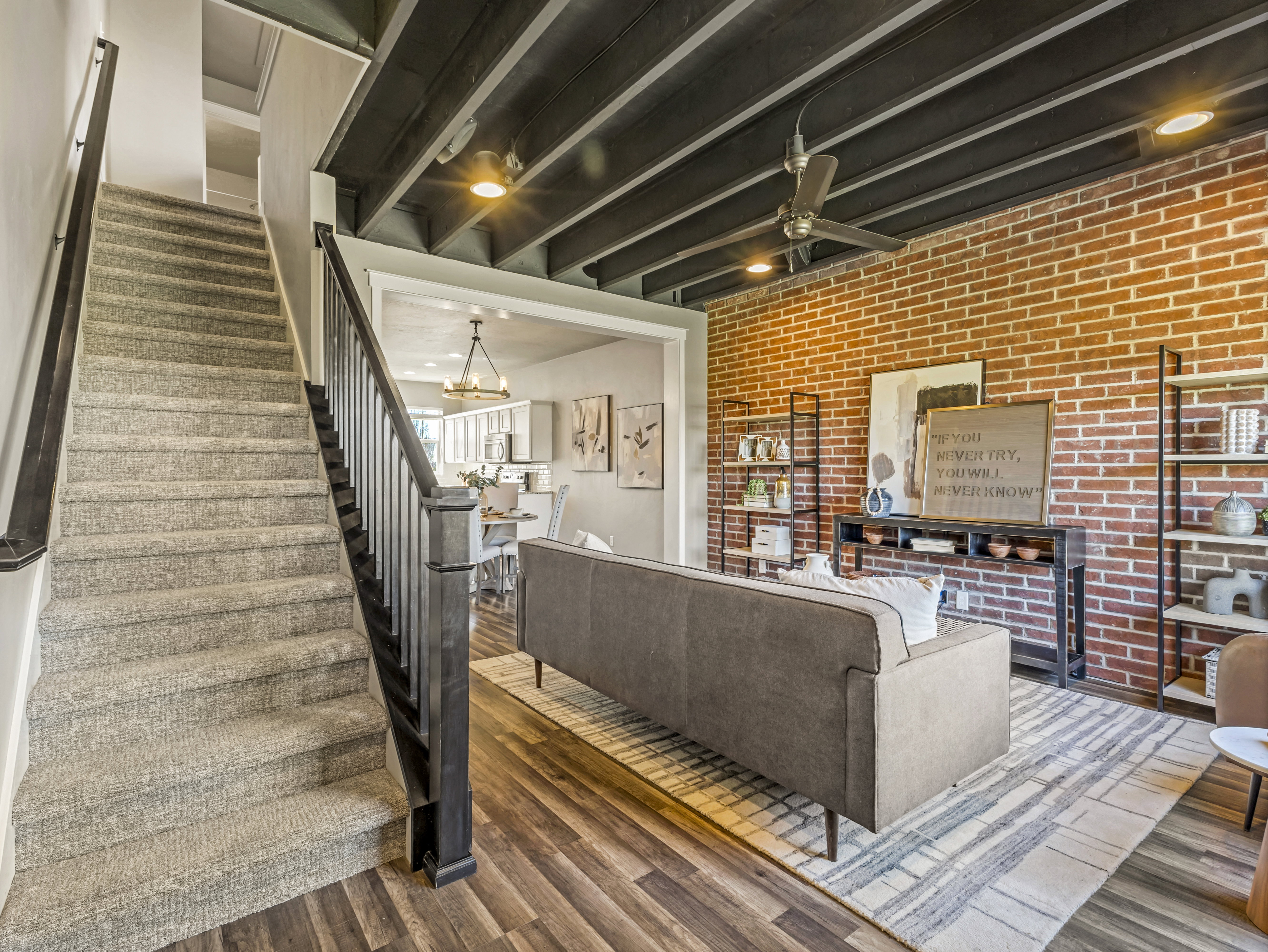 Living room with wood finished floors, brick wall, a chandelier, and ceiling fan