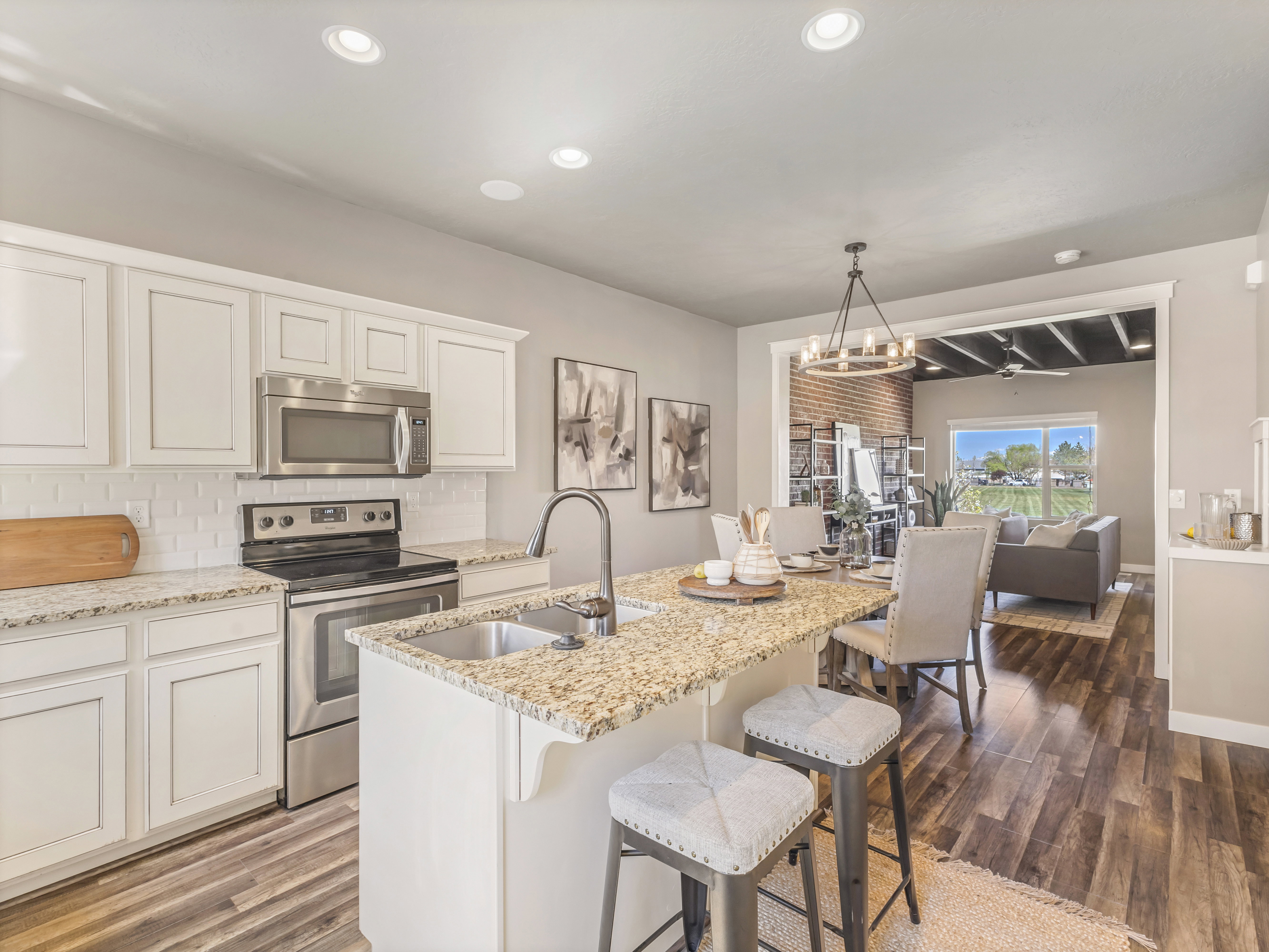 Kitchen featuring stainless steel appliances, white cabinets, light stone counters, and tasteful backsplash