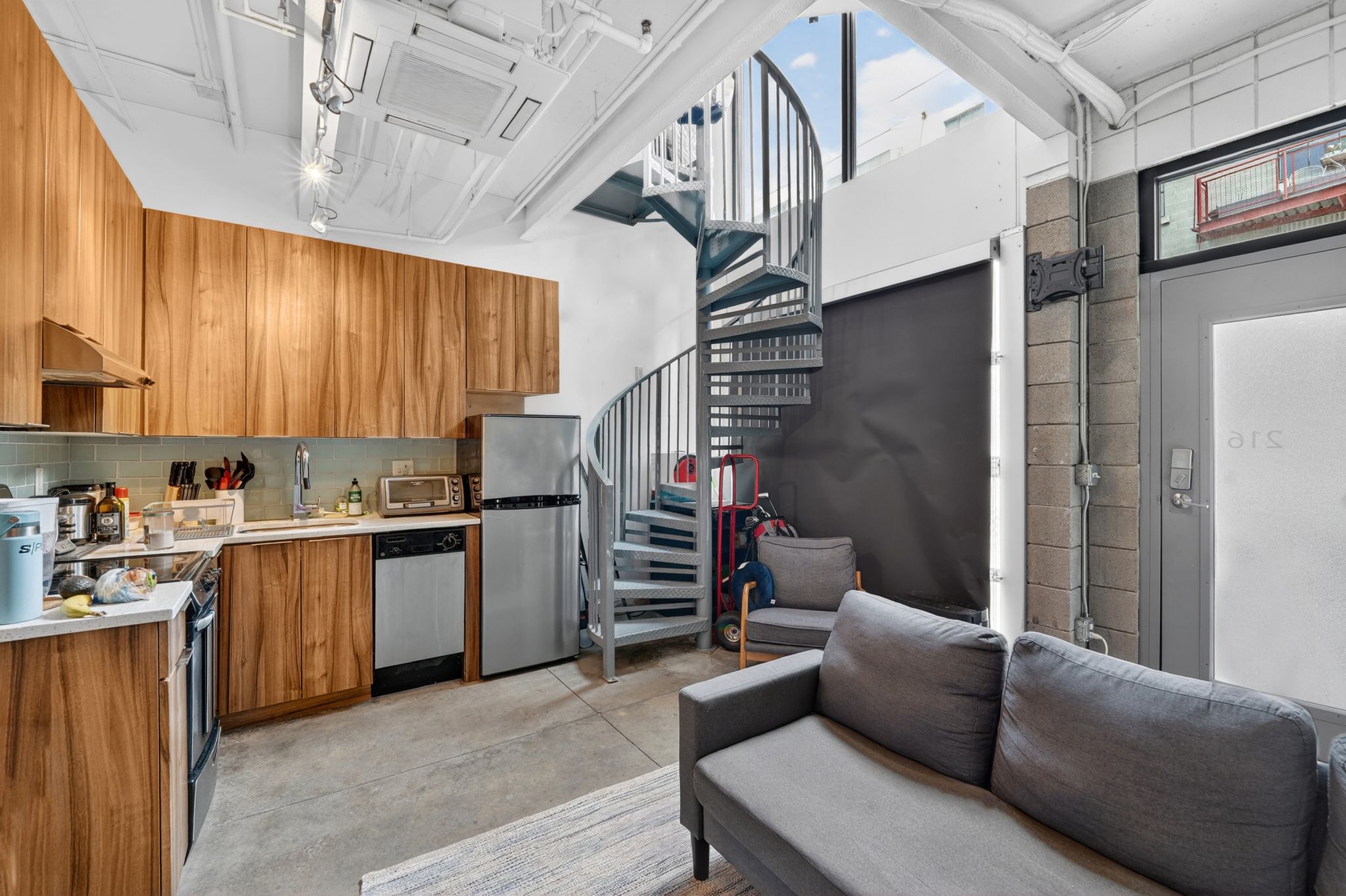 Kitchen featuring wood finish cabinetry, light countertops, concrete flooring, stainless steel appliances, and modern cabinets