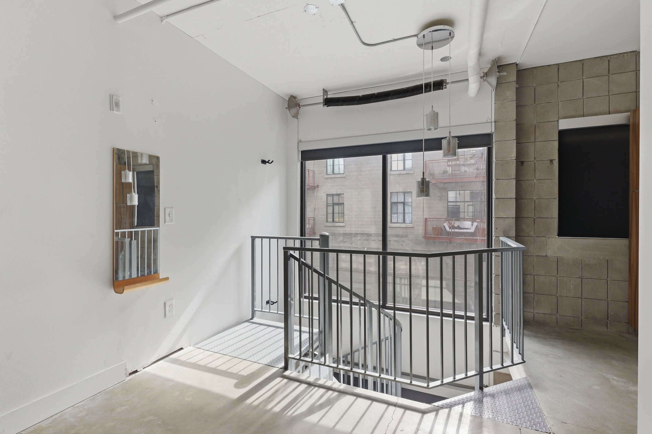 Industrial-inspired interior featuring a metal railing staircase and polished concrete flooring