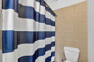 Full bath featuring a shower with curtain and tile walls