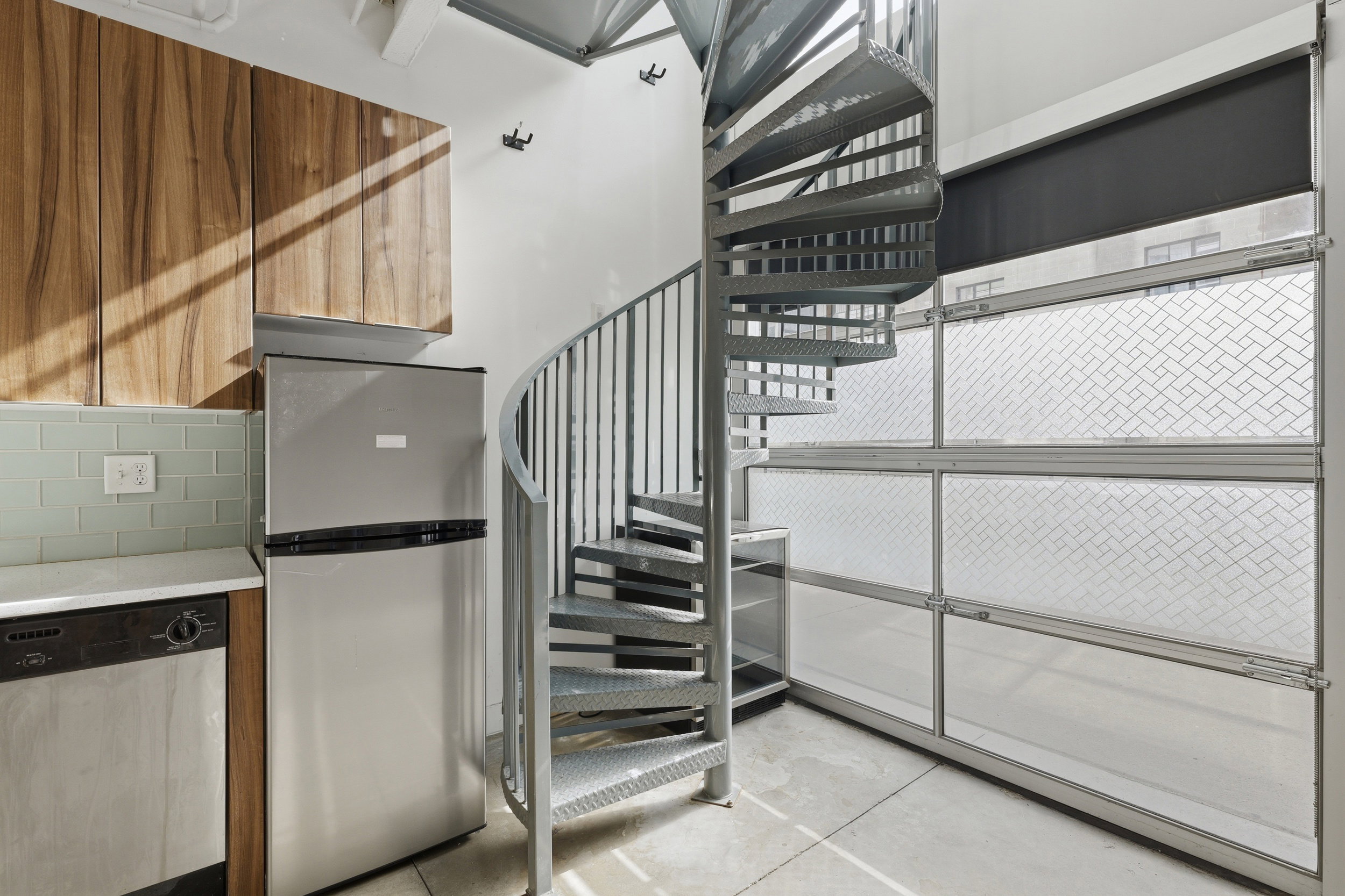 Industrial-style spiral staircase and wall of translucent garage-style windows