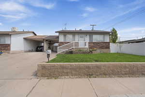 View of front of house featuring driveway, a carport, and brick siding
