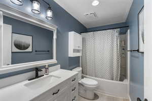 Full bathroom with vanity, shower / tub combo with curtain, and a textured ceiling