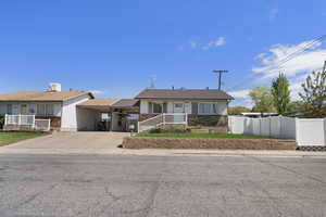 View of front of home featuring concrete driveway, brick siding, and a carport