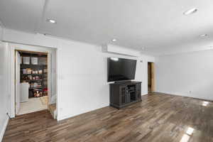 Unfurnished living room with dark wood finished floors, wooden walls, and recessed lighting