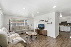 Living area with dark wood-type flooring and recessed lighting