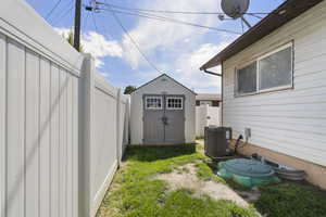 Fenced backyard featuring a storage unit
