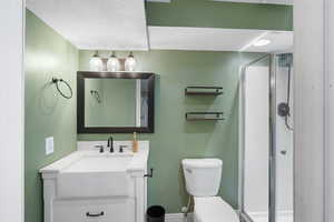 Full bath with vanity, a shower stall, and a textured ceiling