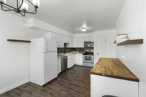 Kitchen featuring stainless steel appliances, wood counters, backsplash, white cabinetry, and dark wood-style floors