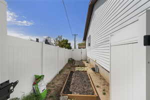 View of side of home featuring a vegetable garden, a fenced backyard, and a gate