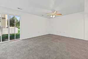 Family room with walkout basement entrance, newer carpet and ceiling fan
