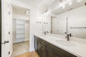 Bathroom with a walk in closet, double vanity, and light carpet