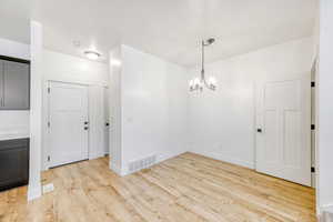 Unfurnished dining area with hanging lights and light wood-style flooring