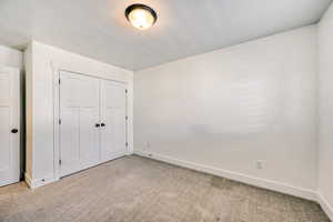 Unfurnished bedroom with light carpet and a closet