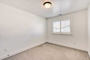 Empty room featuring light carpet and a textured ceiling