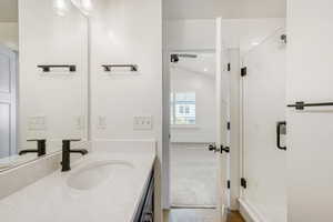 Bathroom featuring vanity, a stall shower, light carpet, and lofted ceiling