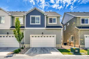 View of front of house featuring a garage, concrete driveway, and stucco siding