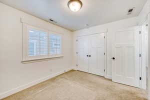Unfurnished bedroom featuring light carpet, a closet, and a textured ceiling