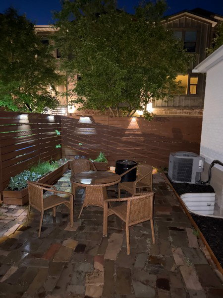 Private courtyard featuring a flagstone patio, wood fence with integrated lighting, and built-in planters
