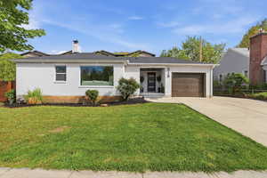 View of front facade featuring concrete driveway, a garage, a chimney, and brick siding