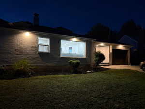 View of front of property with brick siding, a garage, a yard, and a chimney