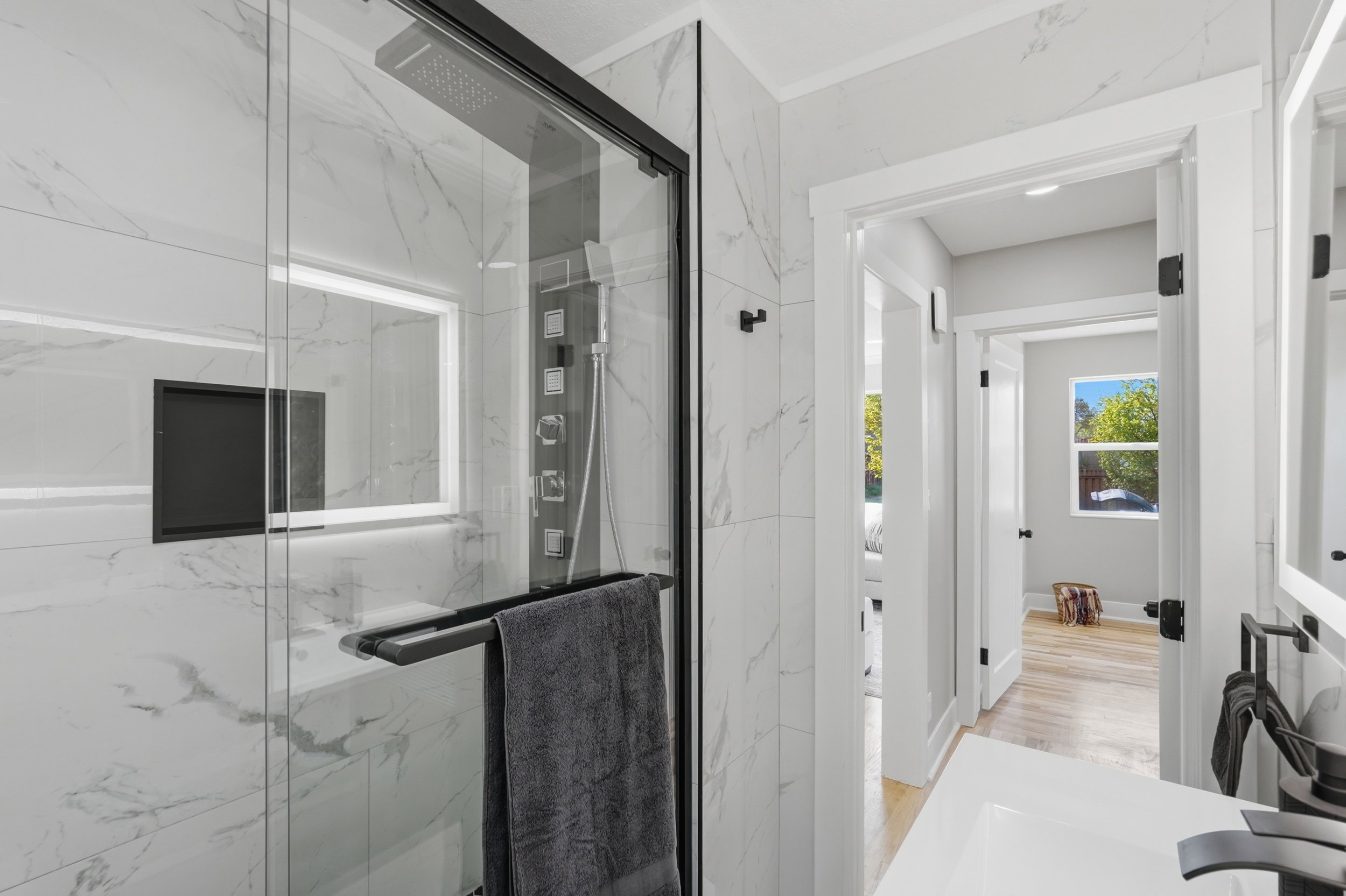 Bathroom featuring a marble finish shower, vanity, and light wood-type flooring