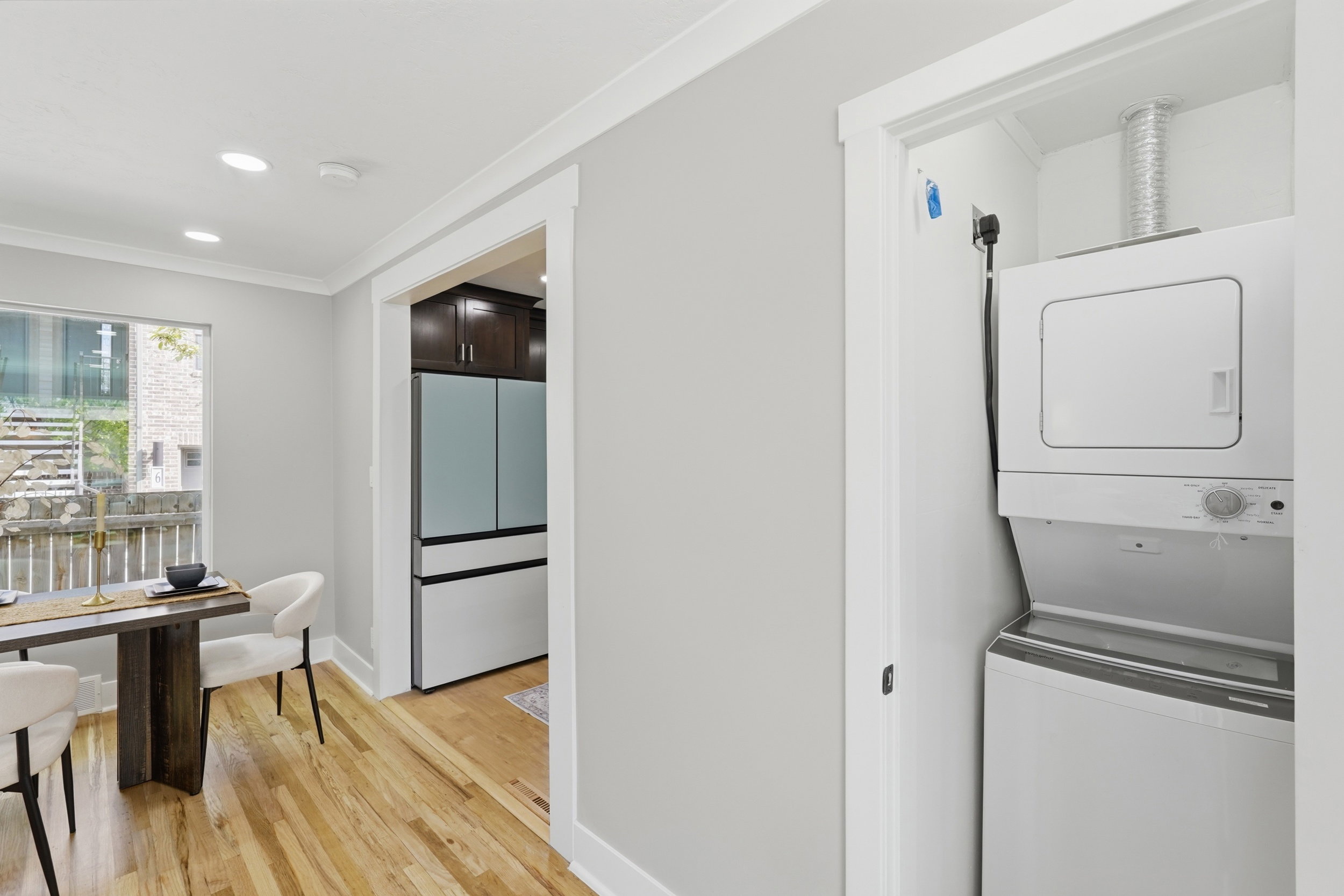 Laundry area featuring crown molding, stacked washer / drying machine, light wood finished floors, and recessed lighting