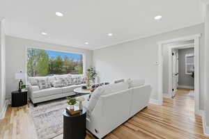 Living room with light wood-type flooring, recessed lighting, and ornamental molding