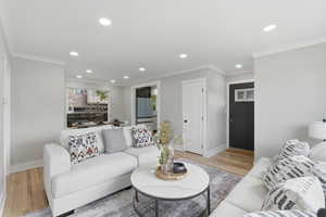 Living area with recessed lighting, light wood finished floors, and crown molding