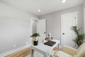 Home office with light wood-style flooring and recessed lighting