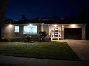 View of front facade with a yard, an attached garage, and driveway