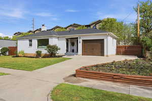 View of front of property with an attached garage, concrete driveway, a chimney, and brick siding