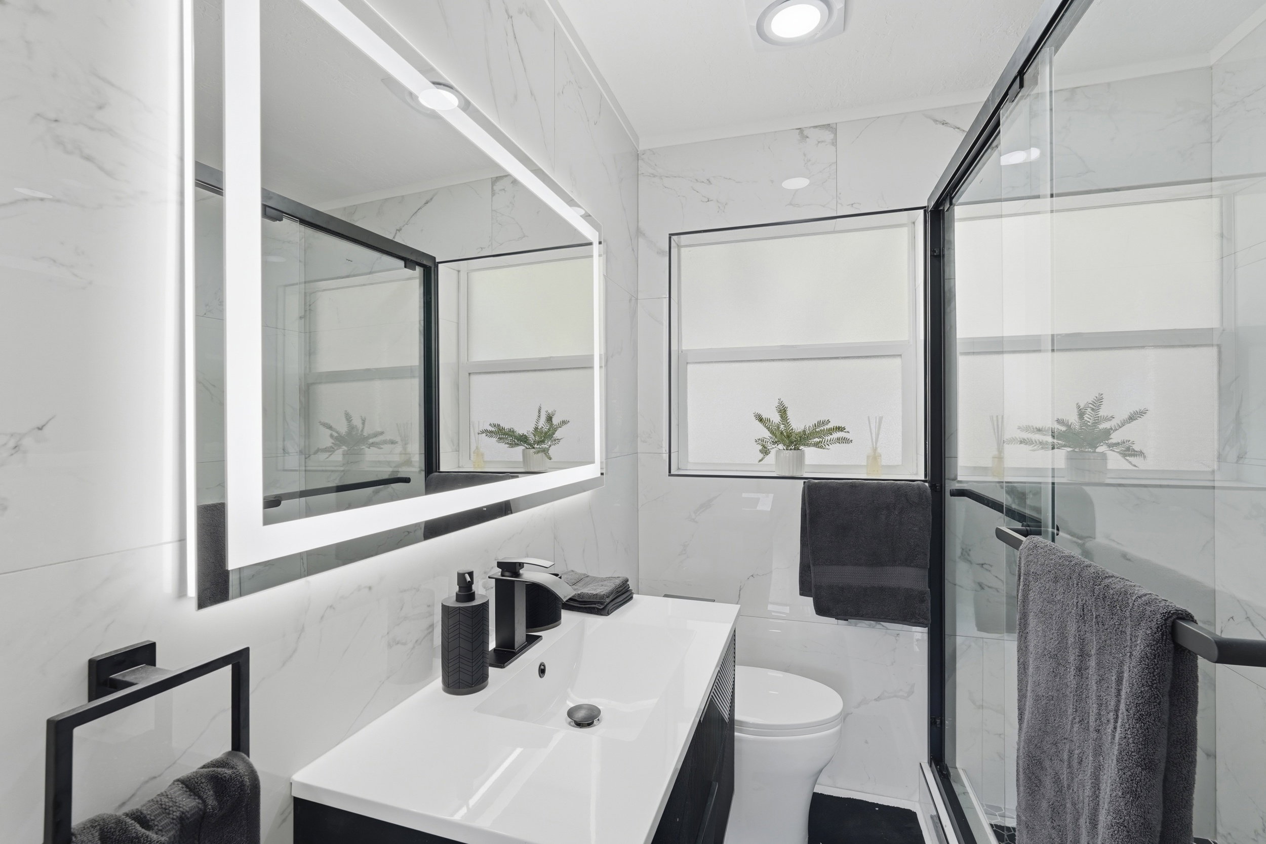 Full bathroom with stone wall, vanity, a marble finish shower, and tile walls