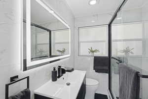 Full bathroom with stone wall, vanity, a marble finish shower, and tile walls