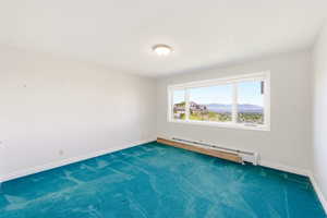 Spare room with a baseboard radiator, a mountain view, and dark carpet