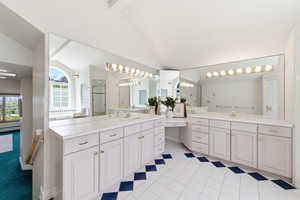 Bathroom featuring lofted ceiling with beams, two vanities, a shower stall, and light tile patterned floors