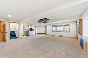 Unfurnished living room with light carpet, beverage cooler, a baseboard radiator, wet bar, and recessed lighting