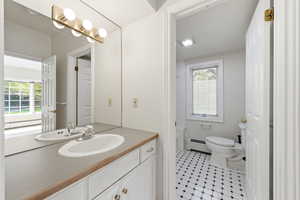 Full bath with vanity and a baseboard radiator