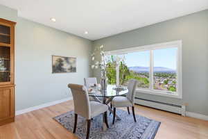 Dining space with a mountain view, a baseboard radiator, light wood finished floors, and recessed lighting
