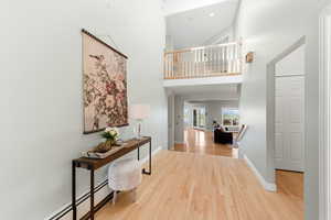 Hallway with light wood-type flooring, a high ceiling, and a baseboard heating unit