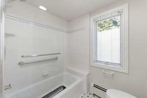 Bathroom with a baseboard heating unit and bathtub / shower combination