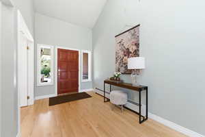 Entryway with light wood finished floors, a baseboard heating unit, and lofted ceiling