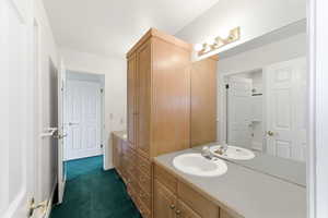 Bathroom with vanity and dark colored carpet