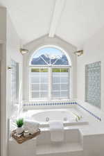 Full bath with a tub with jets, beam ceiling, a mountain view, and plenty of natural light