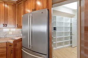 Kitchen featuring wood finish cabinets, stainless steel appliances, light wood-type flooring, and backsplash