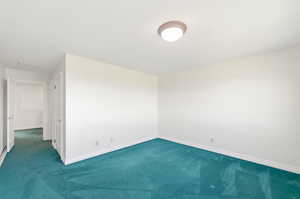 Carpeted spare room featuring baseboards
