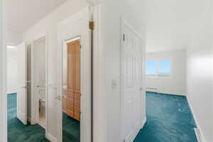 Hall featuring dark carpet and baseboard heating